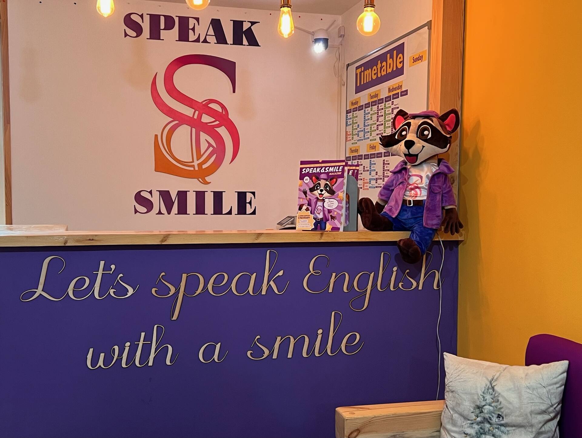 Ресепшен школы Speak & Smile — маскот-енот Спики
